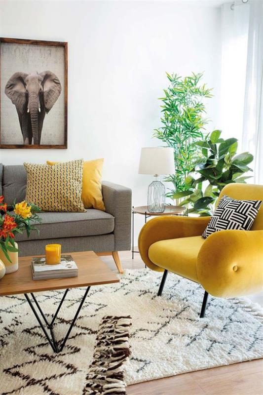 Trendivärit 2021 sisätiloissa harmaa sohva keltainen nojatuoli matto ikivihreät huonekasvit paljon auringonvaloa