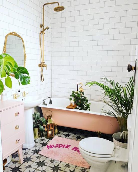 Trooppinen sisustus kylpyhuoneessa eksoottinen tunnelma vapaasti seisova kylpyamme vaaleanpunainen tarvikkeet kultainen aksentti suihku peilikehys