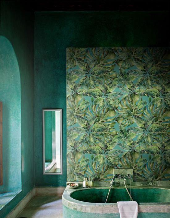 Trooppinen sisustus kylpyhuoneessa vihreät seinät tapetti eksoottisia lehtiä sisäänrakennettu kylpyamme seinäpeili taustaikkunassa vasemmalla