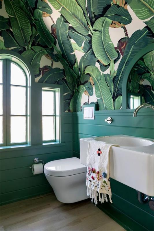Trooppinen deco kylpyhuoneessa kaunis tapetti suuret lehdet valkoiset kylpyhuonekalusteet wc -lattialaatat vasen ikkuna
