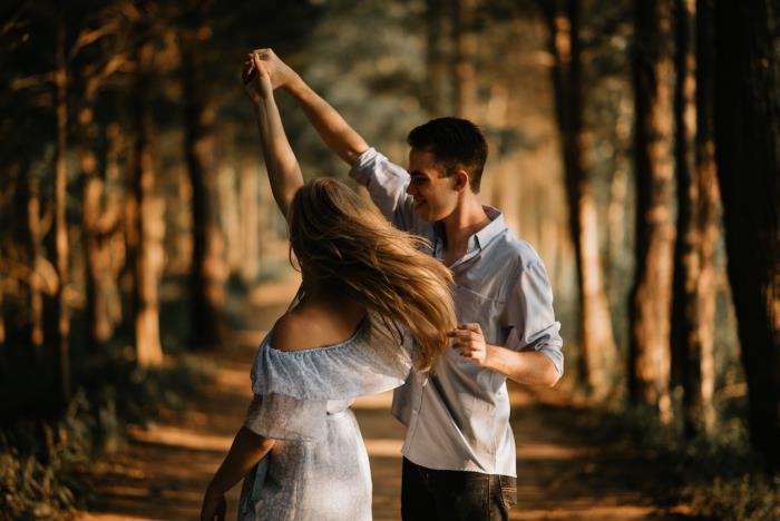 Rakastunut hänen onnellinen nuori parinsa tanssii metsässä ruusunpunaisilla laseilla