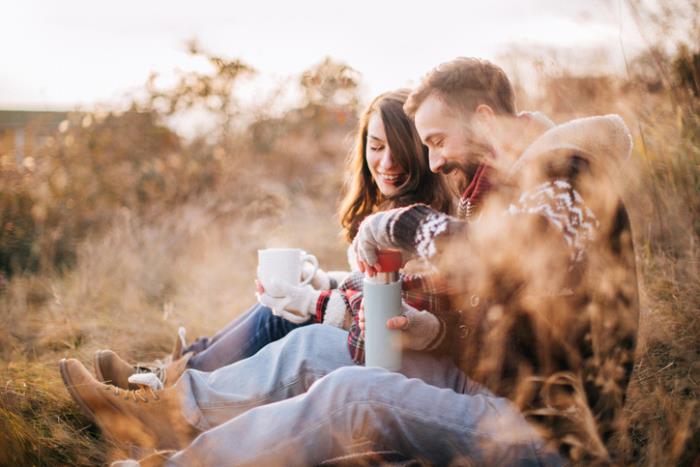 Metsävaelluksen aikana rakastunut nuori pari viettää onnellisesti kahvitauon luonnossa ja viettää hyvää aikaa yhdessä