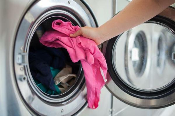 Haiseva tahnainen pesukone poistaa vaaleanpunaiset pyykit