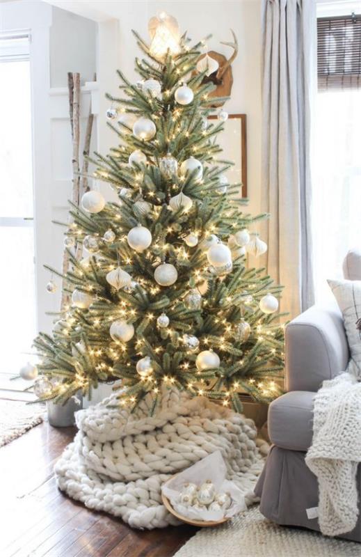 Joulukuusi koristaa monia pieniä valoja valkoisissa ja hopeisissa kiiltävissä joulukuusi palloissa