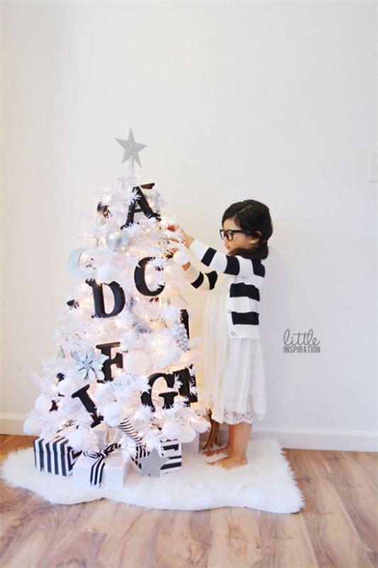 Joulukuusi koristellaan valkoisella ja hopealla pieni puu valkoisella koristeella mustalla kontrastilla isot kirjaimet pikkutyttö