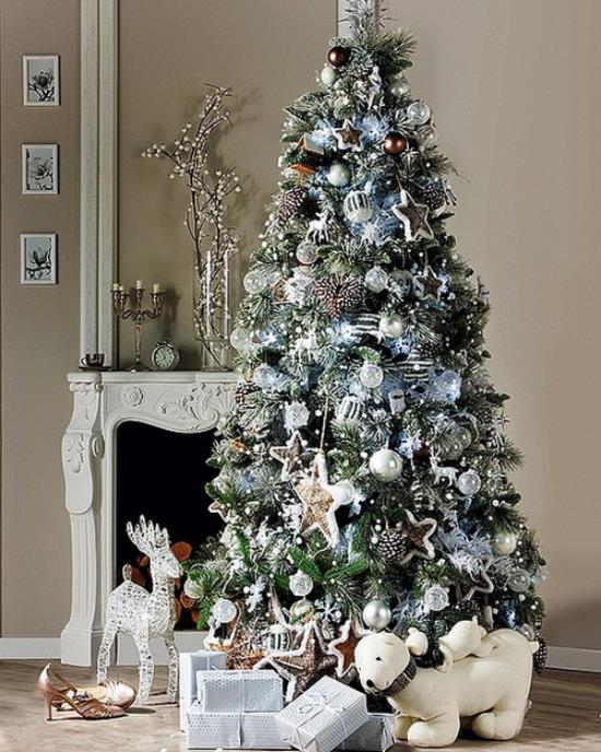 Koristele joulukuusi valkoisella ja hopealla takan edessä upeasti koristeltuja hirvikoiralahjoja