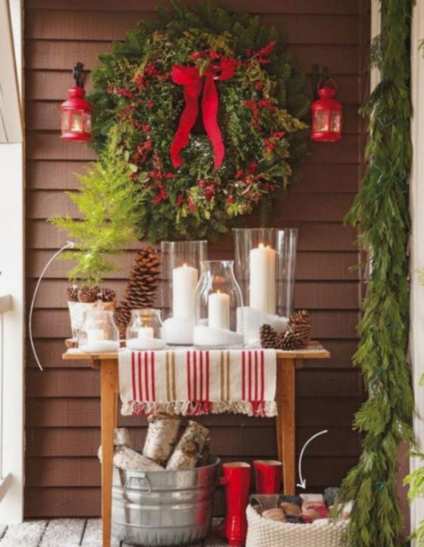 Joulukoristeita parvekkeelle paljon kuusen vihreää, punaiset jouset, punaiset saappaat, valkoiset kynttilät, kodikas ja houkutteleva