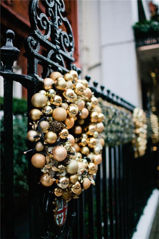 Joulukoristeita kultaa ja mustaa seppeleitä kultaisia ​​joulupalloja mustalla aidan taustalla