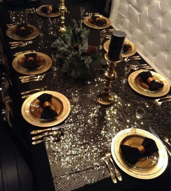 Joulukoristeet kultaa ja mustaa, juhlallisesti katettu ruokapöytä, erittäin näyttävät, kimaltelevat pöytäliinat, kulta -astiat, mustat lautasliinat