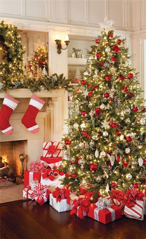 Joulukoristeita punaisesta ja kultaisesta joulukuusta koristeltu takan vieressä Joulupukin saappaat takan päällä lukuisia lahjavaloja