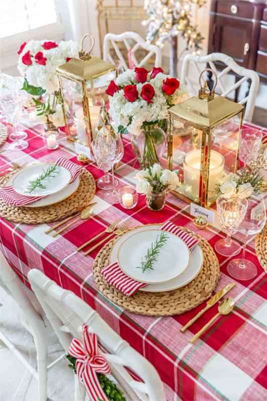 Joulukoristeet punaisella ja kullalla juhlallisesti katettu pöytä ruudullinen pöytäliina paljon joulukoristeita pöytäkoristeina punaisia ​​ja valkoisia ruusuja
