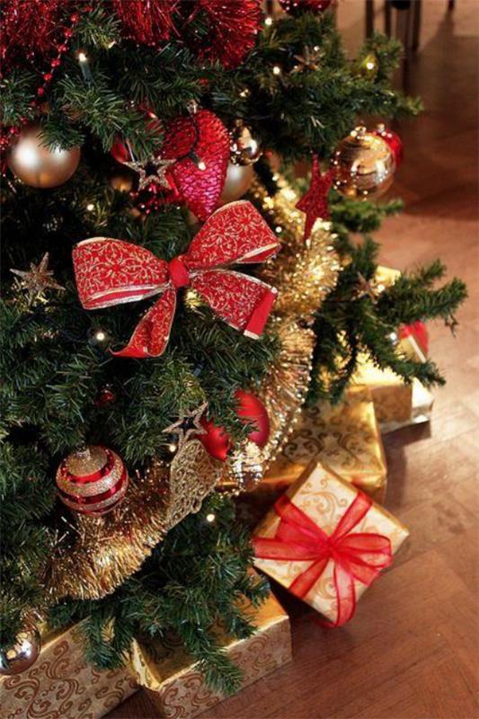 Joulukoristeet punaisella ja kullalla Suuret punaiset jousipallot seppelevät lukuisia lahjoja joulukuusi alla