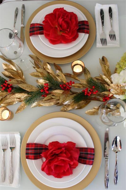 Joulukoristeet punaisilla ja kultaisilla ruudullisilla nauhoilla punaiset kukat koristavat jaloja ruokailukynttilöitä kultaisia ​​aksentteja
