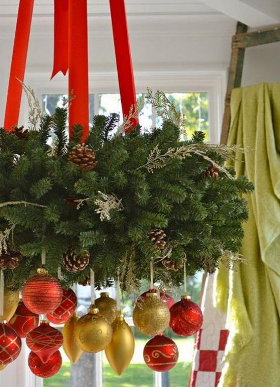 Punaiset ja kultaiset joulukoristeet Kattokruunussa roikkuu reheviä joulukoristeita, paljon mäntyvihreitä käpyjä