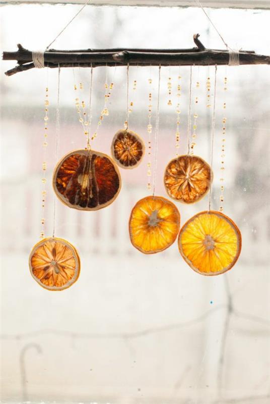 Joulukoristeet näpertelevät appelsiininkuoren seppeleitä ikkunan koristeluun