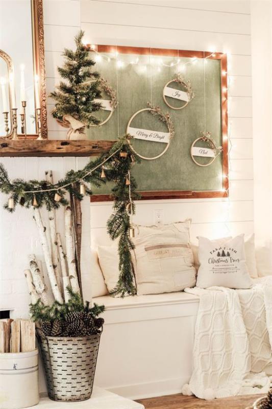 Talvikoriste olohuoneessa, valkoinen penkki takan vieressä, koristeltu yksinkertaisilla asioilla, muutamia vihreitä männynkäpyjä ämpäriin