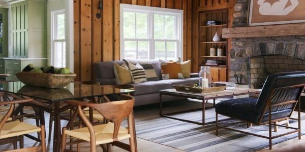 Kodin tarvikkeet modernissa olohuoneessa, jossa on paljon puuta ja lasipöytä kiviseinä