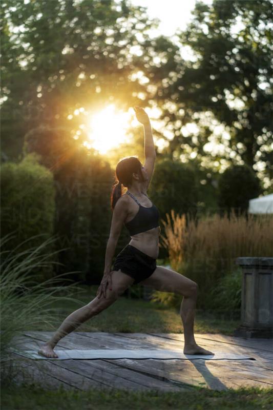 Joogapuutarha asettelu ja suunnittelu auringonlaskun nuoren naisen joogamattoharjoituksissa ulkona