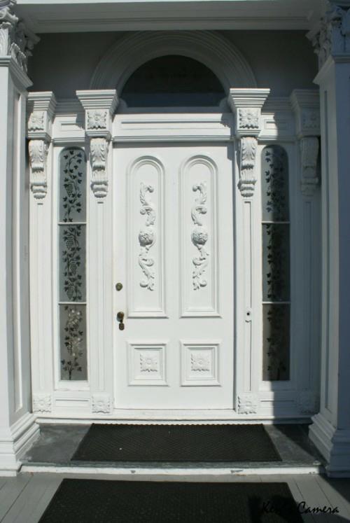 vanhanaikaiset koriste -aiheet koristavat valkoista ulko -oven muotoilua