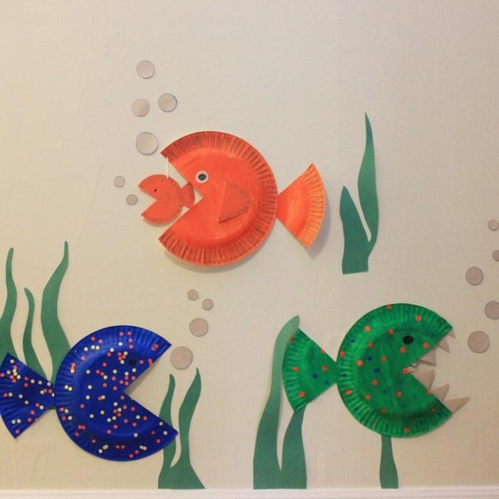 näpytellä värillisiä kaloja merellä paperilevyillä