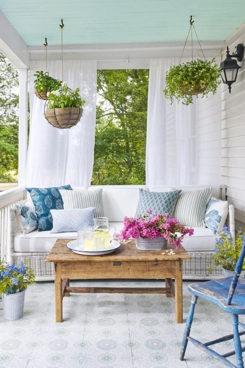 Katettu veranta sinisellä ja valkoisella, kuten pieni puutarha, ripustaa roikkuvat korit