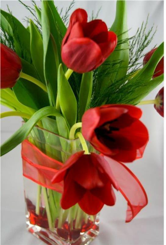 kukkien järjestäminen pöydän koristeluideoita tulppaanien punaisella nauhalla