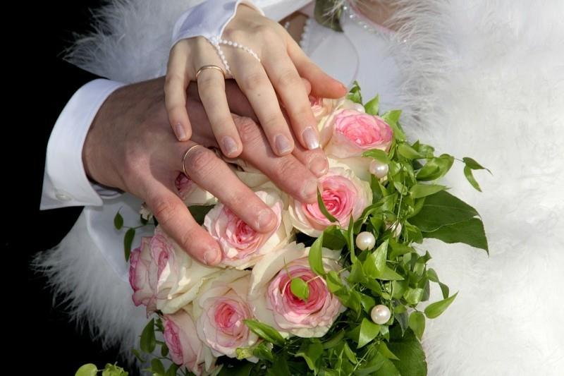 morsian ja sulhanen kädet ruusut sormukset