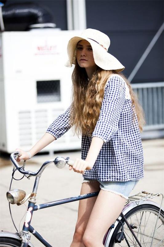 nainen aurinkohatulla pyörällä