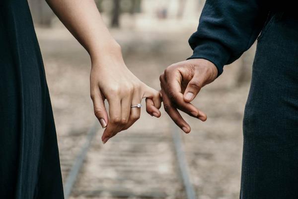 kolme horoskooppia rakastava pari käsi kädessä nuori nainen yllään kihlasormus