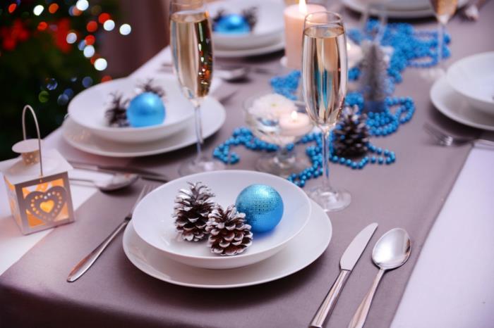 juhlapöydän koristelu Joulun sininen aksentti männynkäpyjä lautasella