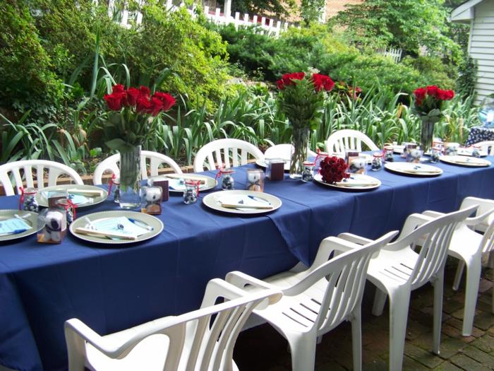 juhlapöydän koristeet sininen pöytäliina punaiset ruusut valkoiset tuolit