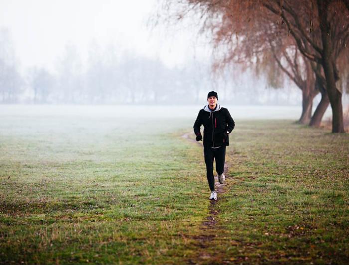 pysyä terveenä ja onnellisena talvella nuori mies lenkkeilee hyvässä kunnossa huonolla säällä