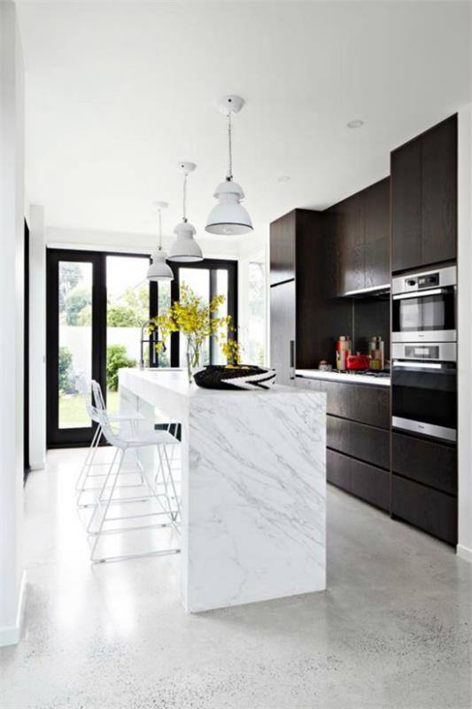 harmaa lattia betoni moderni keittiö valkoinen keittiösaari mustat kaapit riippuvalaisimet