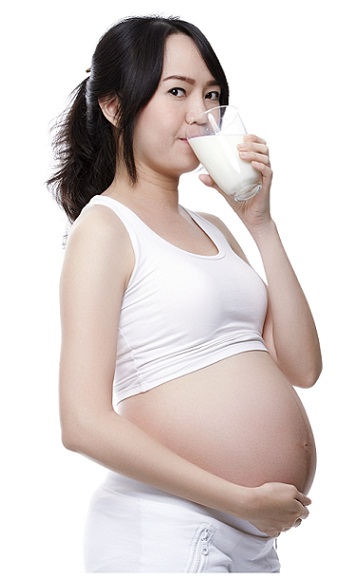 Gravid kvinde, der drikker mælk med gurkemeje