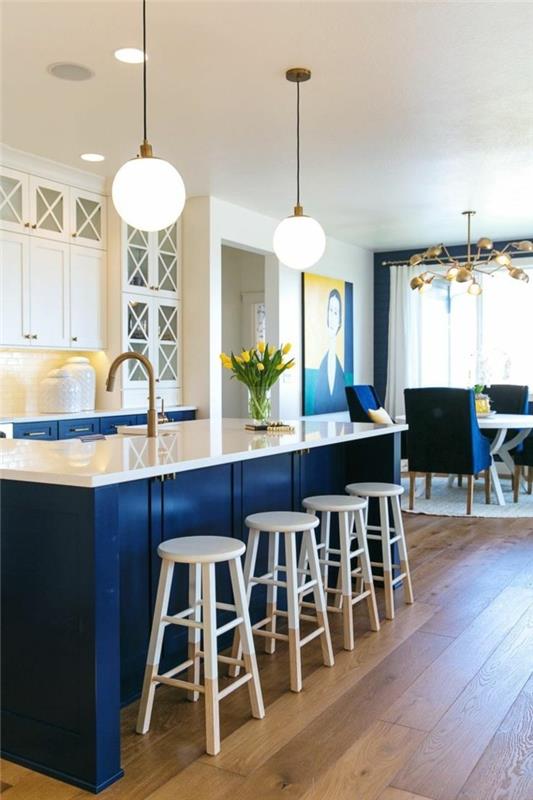 keittiövärinen, sininen keittiösaari, jossa valkoiset seinäyksiköt ja puulattia
