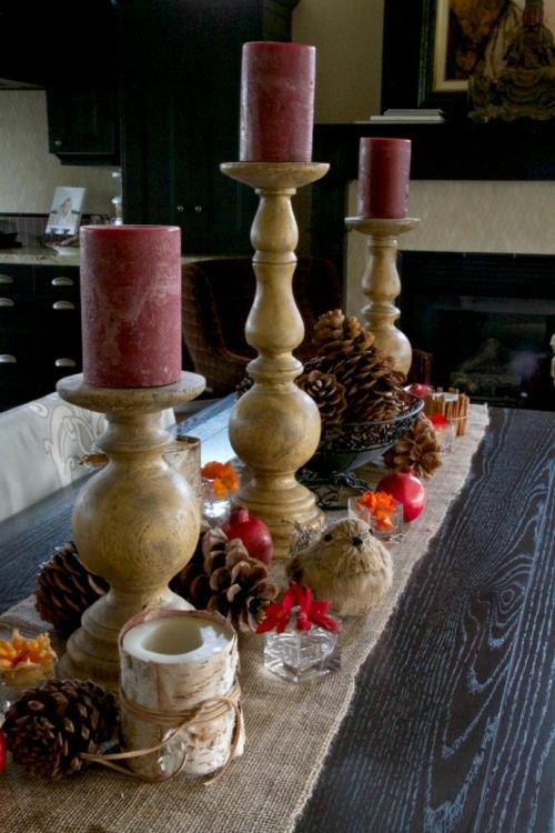 Kynttilät koristavat viininpunaista kolmella puisella kynttilänjalalla