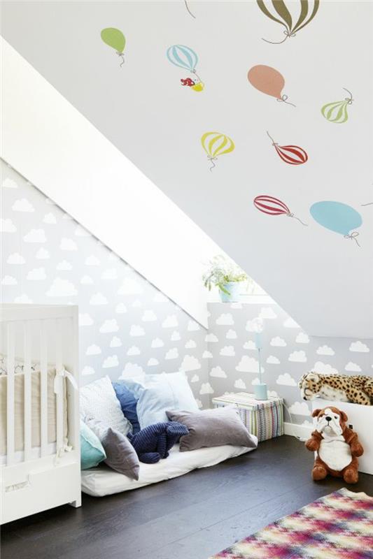 Lastenhuone, jossa viisto katto, vauvan huone, vauvan sänky, viihtyisä nurkka, leikkialue, pehmolelut, ilmapallo, tapetti, pilviä