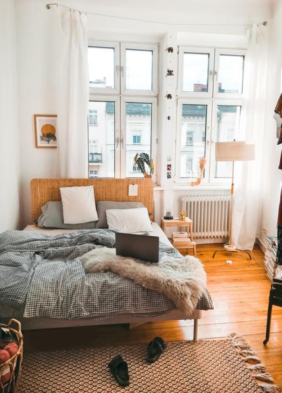 pieni makuuhuone puulattia puinen sänky beige peitto iso ikkuna