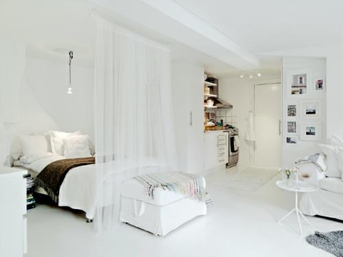 pieni asunto näyttää läpinäkyvien valkoisten verhojen koon sängyssä