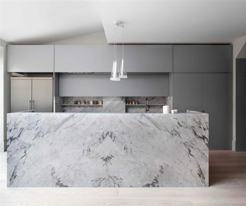 marmorinen keittiösaari, jossa on karkeat harmaat keittiökaapit, modernit kattovalaisimet