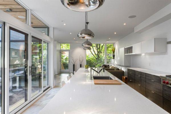 minimalistinen asuinpaikka soikeat kiiltävät metalliset riippuvalaisimet valkoisen keittiön saaren päällä