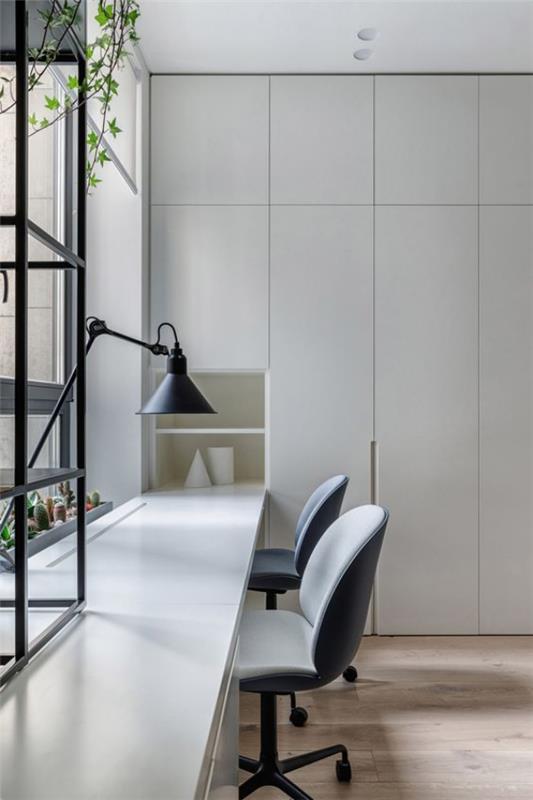 minimalistinen kotitoimisto paljon päivänvaloa sisältävä pöytä ikkunan edessä harmaa pöytävalaisin hallitsee