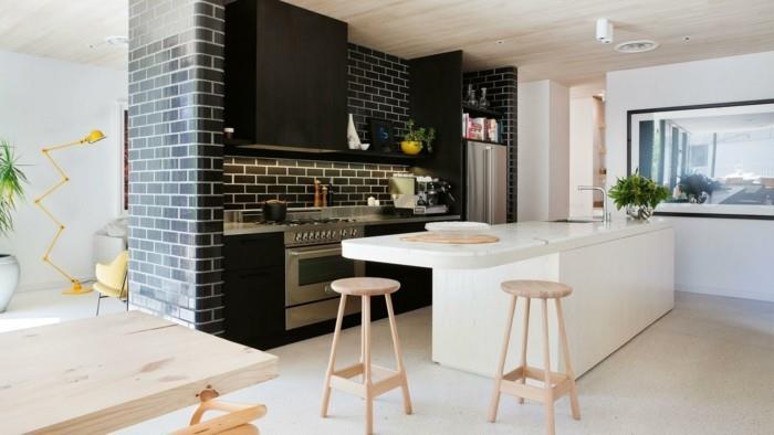 moderni elävä valkoinen keittiösaari ja mustat seinälaatat