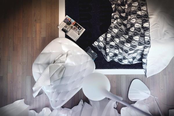 Moderni design -makuuhuoneen verhoiltu valkoinen nojatuoli ja kuviollinen peitto