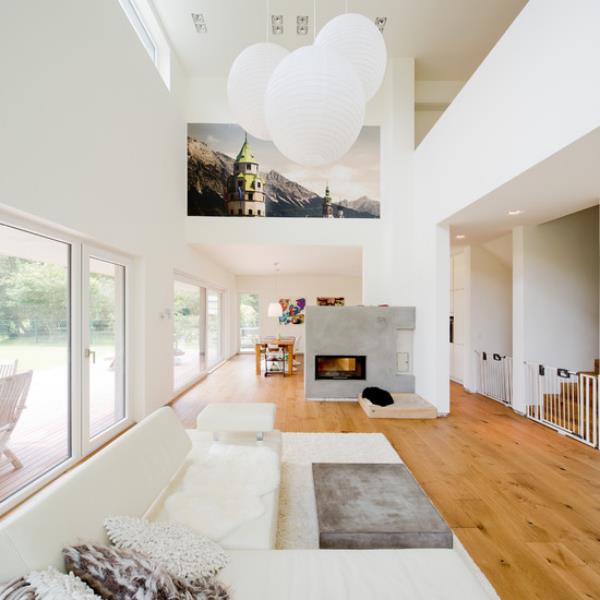 moderni olohuone kahdella tasolla tyylikäs sisustus valkoisissa riippuvalaisimissa seinämaalaus vaalea puu lattialla betoniseinä, jossa on takka