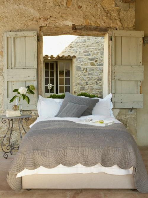 romanttiset makuuhuoneen kalusteet luonnonkivillä ja karkeilla puisilla ikkunaluukuilla