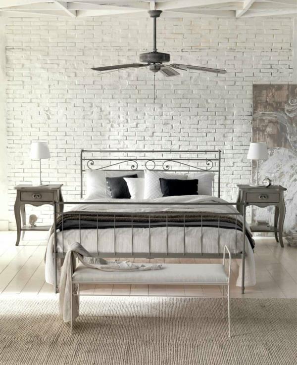 makuuhuoneessa on luonnollista tunnelmaa, yksinkertainen metallinen sängyn penkki ja tuuletin