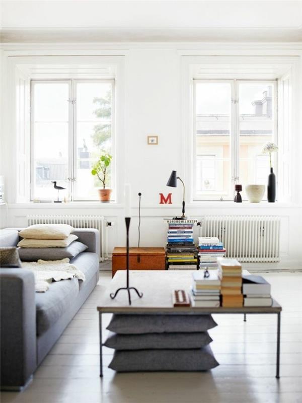 Skandinaavisesti sisustettu olohuone design harmaa sohva heittää tyynyt kirjoja