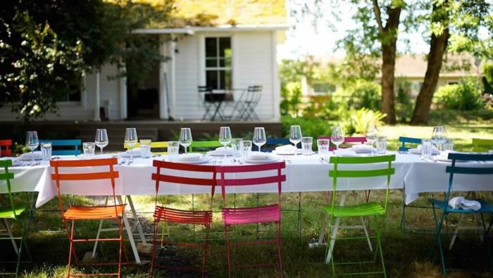 kesäjuhlien sisustus valkoiset pöytäliinat värilliset puutarhatuolit