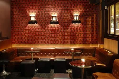 surrealistinen seinätaustakuva seinävalaisimet nahkainen sohva pyöreä koristeellinen lasipöytä